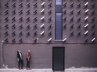 two women facing security camera above mounted on structure