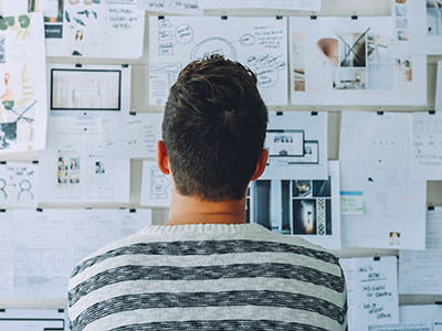 Man Wearing Black and White Stripe Shirt Looking at White Printer Papers on the Wall