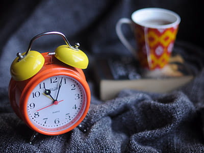 orange and yellow analog alarm clock at 11:03