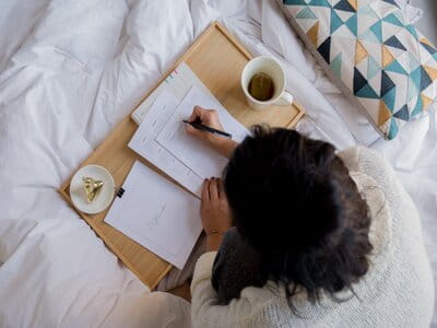 Girl in bed reading a working from home guide